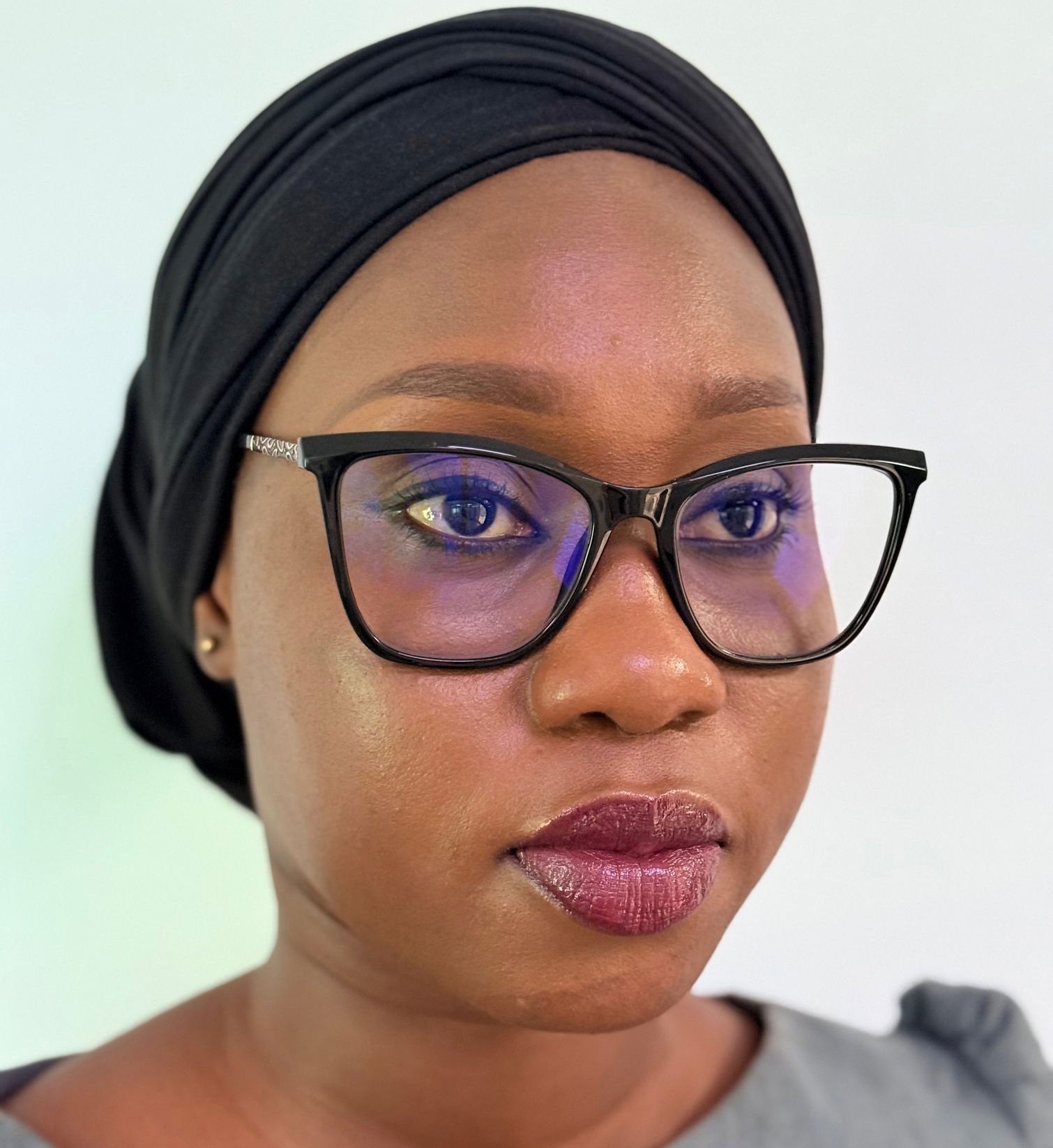 Fatou S.M Jaiteh - 01 A stylized graphic of a green tree with four horizontal layers of leaves and a brown trunk, resembling a palm tree. The trunk is centrally aligned, and there is a green crescent shape at the bottom. A small green crescent sits at the top of the tree.